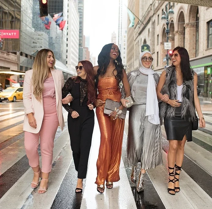 5 women dressed up walking down city street