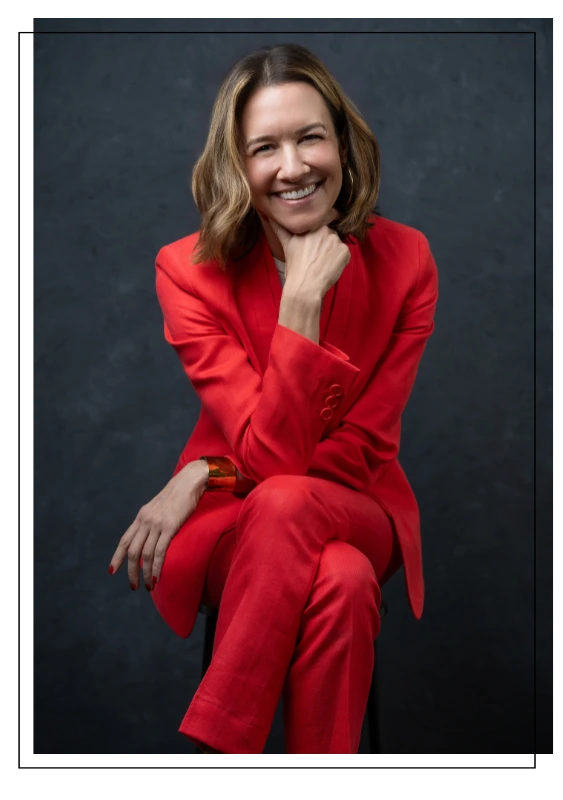 martha magrina in pink pant suit sitting on stool